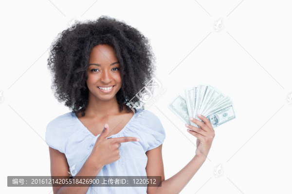 年輕的微笑的女人用卷發(fā)指著一個風扇的美元紙幣