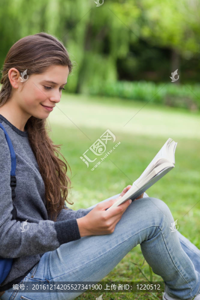 年輕輕松的女孩在鄉(xiāng)村的草地上看書