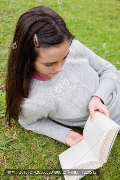 年輕女子躺在草地上看書