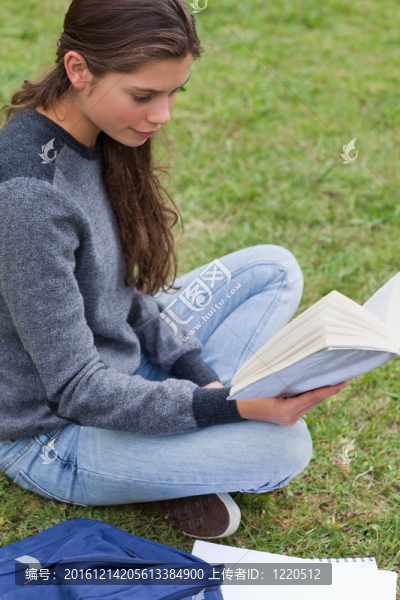 悠閑的小女孩坐在草地上看書