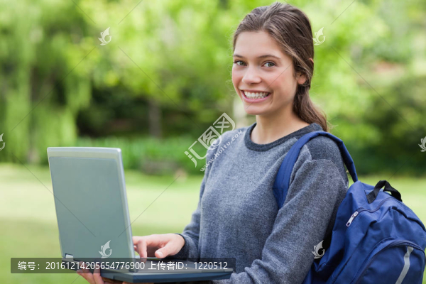 年輕女孩抱著她的筆記本電腦，站起來，并期待在相機前