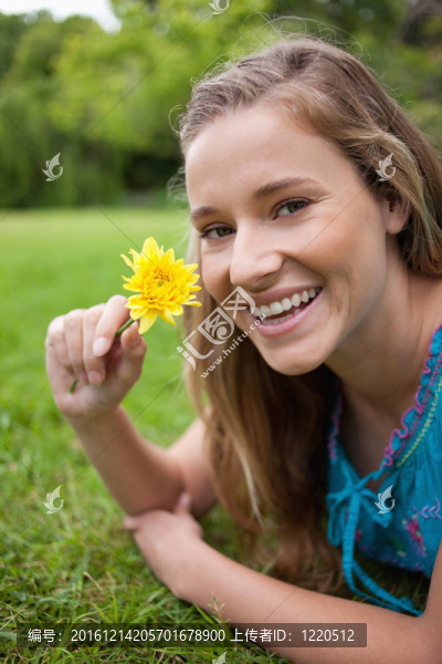 微笑的少年抱著美麗的花朵躺在草地上