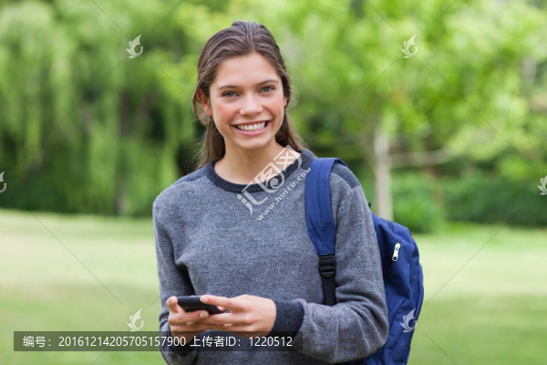 年輕女子微笑著看著相機(jī)一邊發(fā)短信