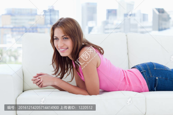 年輕女子一邊看著一邊微笑著躺在舒適的沙發(fā)上