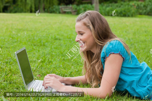 年輕女孩微笑著看著她的筆記本電腦躺下來