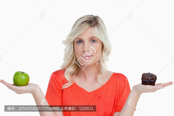 年輕的女人抱著一個巧克力松餅和她手中的青蘋果