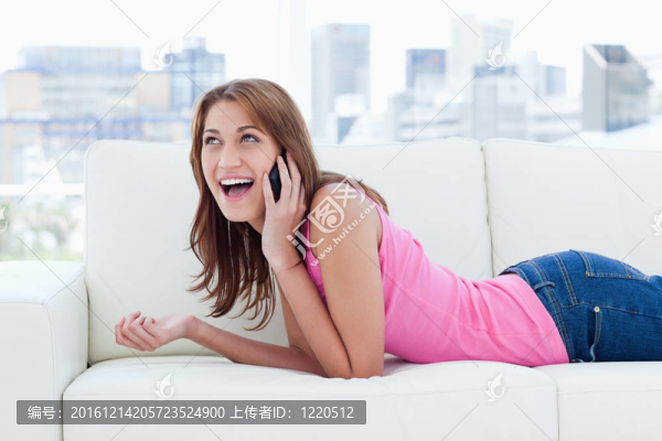 微笑的青少年躺在沙發(fā)上，一邊看著電話一邊聊天