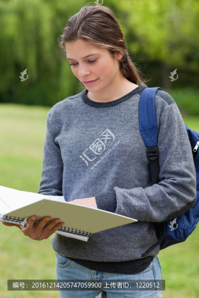年輕女子在公園里站著看書