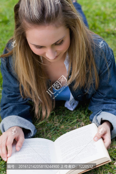 年輕輕松的女孩躺在草地上看書