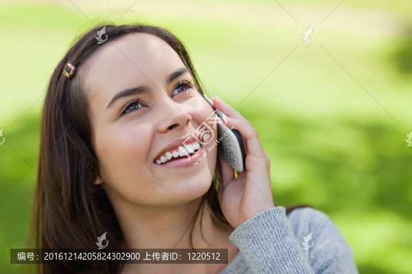 年輕的微笑的女人在電話里仰望