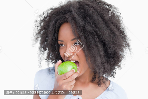 年輕女子一邊看著一邊吃著一個青蘋果