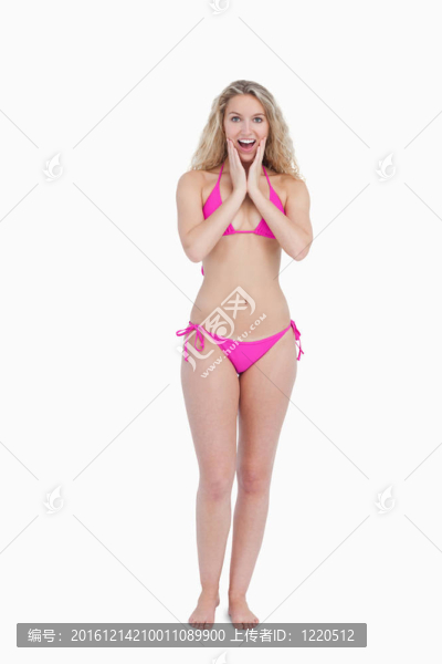 快樂女人在穿泳裝時雙手放在臉頰上表現(xiàn)出驚訝