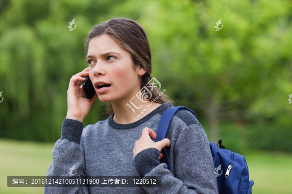 年輕的平靜女孩站在農(nóng)村邊打電話