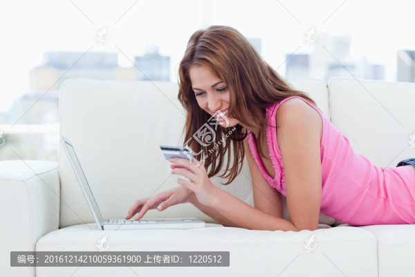 年輕女子看著她的信用卡號碼在網(wǎng)上購物