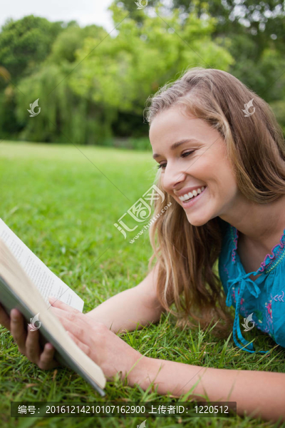 年輕的女孩在看一本書，一個公園而笑