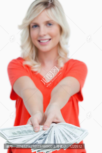 一個(gè)微笑的年輕漂亮女人持有的鈔票的扇子