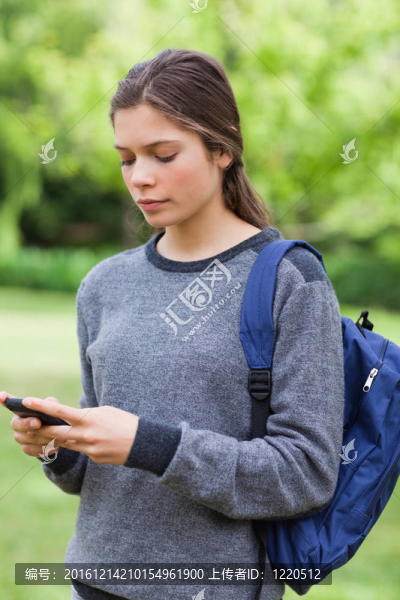 一個年輕認(rèn)真的女孩站在農(nóng)村時用手機(jī)發(fā)短信