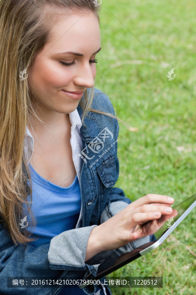 年輕的和平女子坐在鄉(xiāng)下觸摸她的平板電腦