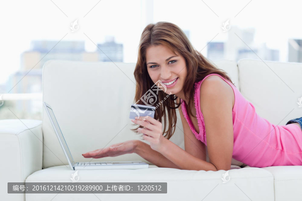 年輕女子拿著信用卡一邊露出燦爛的笑容
