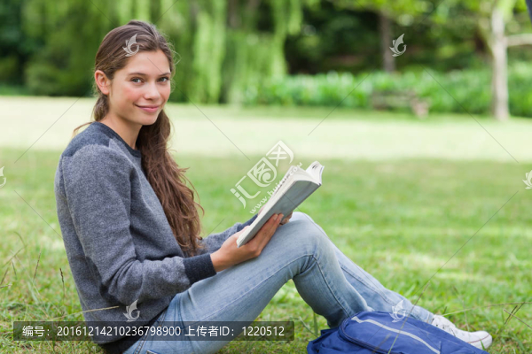 微笑的女孩在鄉(xiāng)下的草地上抱著一本書
