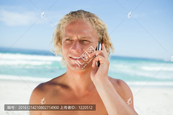 金發(fā)男子站在海洋前用手機