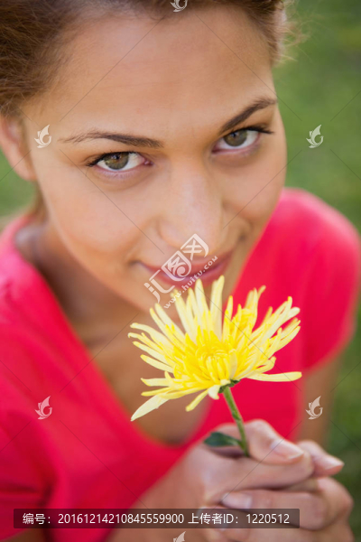 女人抬頭看，手里拿著一朵黃色的花