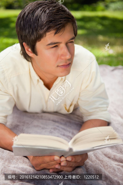 當他躺在草地上的一張灰色毯子上看書時，他看著身邊的人
