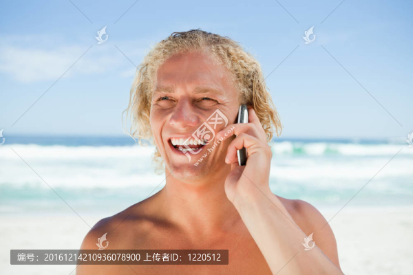 微笑的人站在沙灘上用手機(jī)