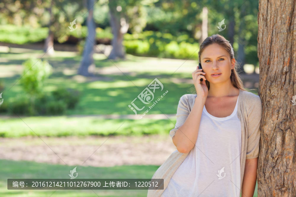 手機上的女人靠在樹上