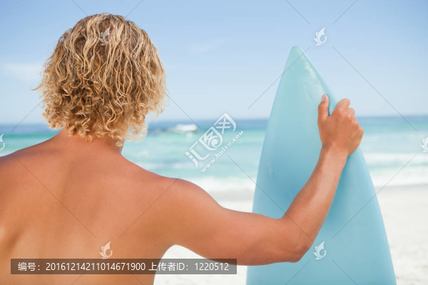 一個年輕的金發(fā)男人抱著一個棲息的沖浪板