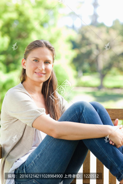 微笑的女人在公園長椅上享受陽光