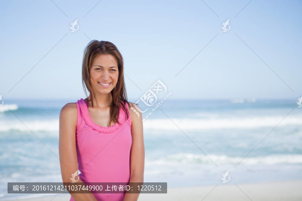 年輕的微笑女子站在前面的海上
