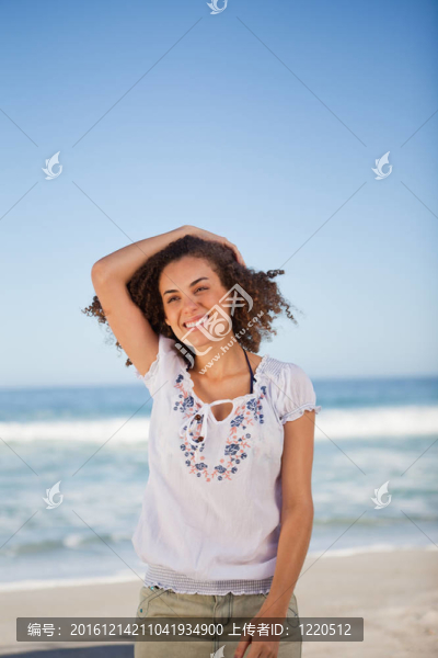 年輕的微笑的女人拿著她的頭發(fā)在海灘上