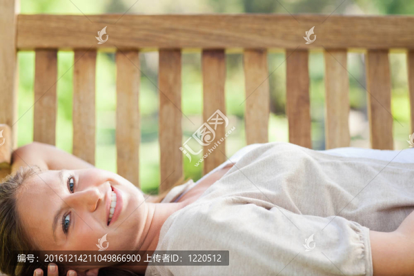 微笑的女人躺在公園長椅上