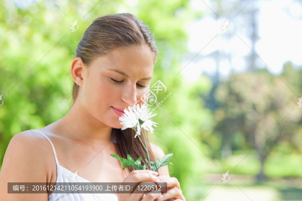 在公園里聞到花的女人