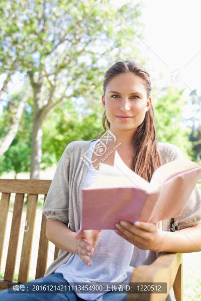 女人坐在公園長椅上看書