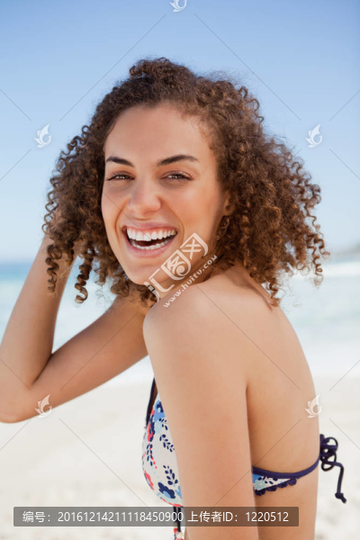 年輕的女人穿著比基尼在沙灘上呈現(xiàn)出巨大的微笑