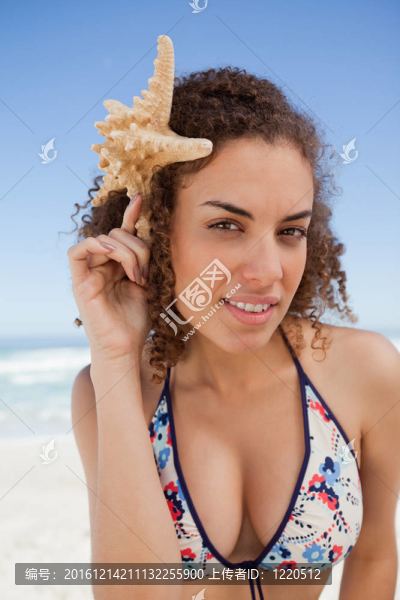 年輕迷人女子抱著海星在她的頭旁邊