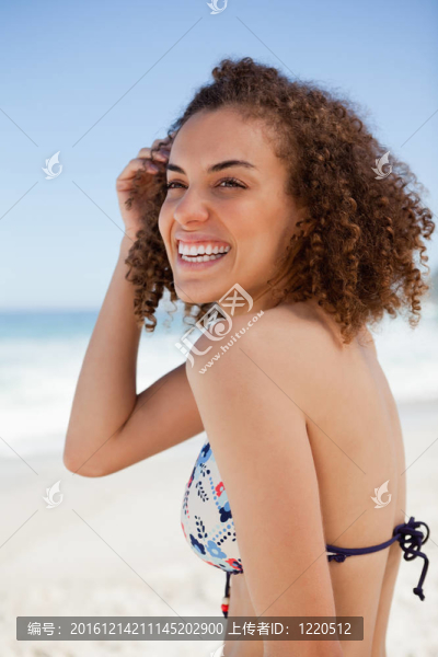 微笑的女人一邊看一邊，同時(shí)把她的手放在她的耳朵旁邊