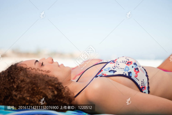 一個(gè)年輕女子午睡在海灘上的側(cè)視圖