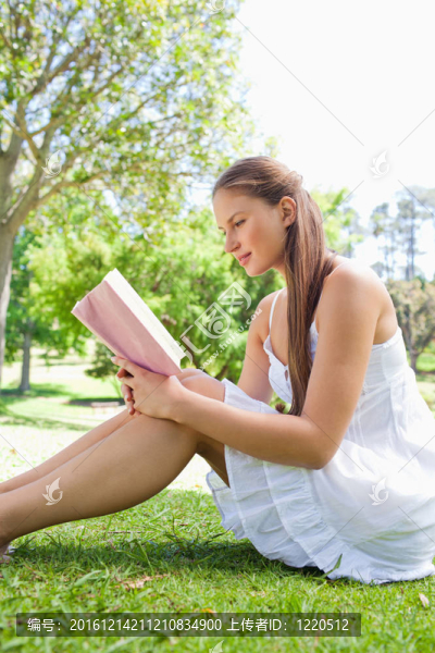 一個女人在草地上看書的側視圖