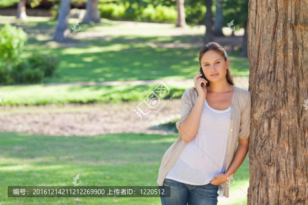 婦女在電話靠在樹上