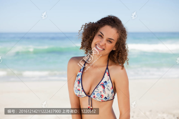 微笑的年輕女子穿著泳裝站在海邊