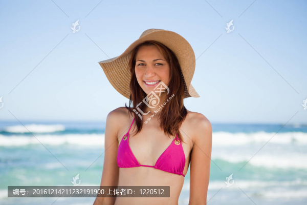 微笑的少女在海灘上戴著帽子