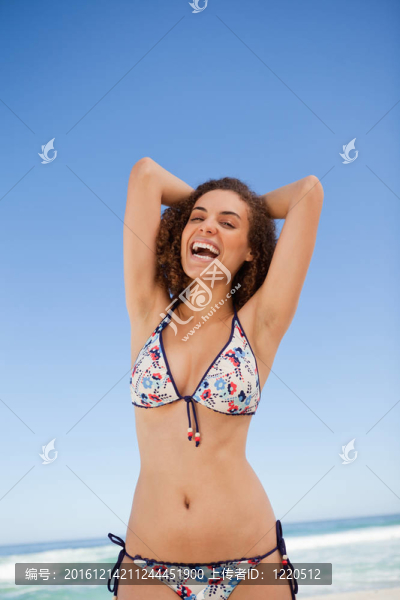 年輕女子在海灘上曬日光浴而笑