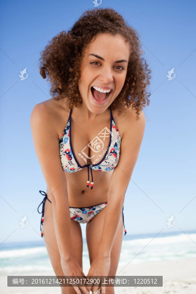 年輕的女人靠著身子在沙灘上比基尼站