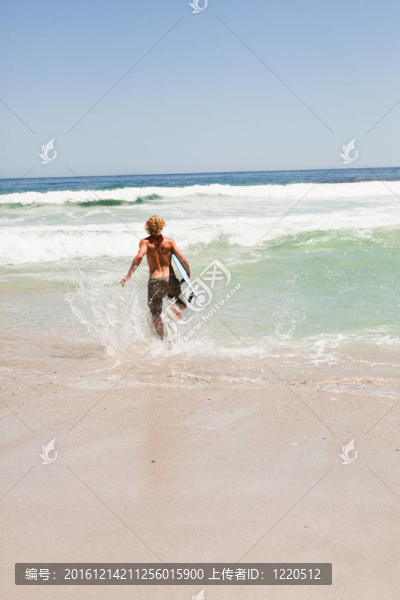 金發(fā)年輕人跑在水與他的沖浪板
