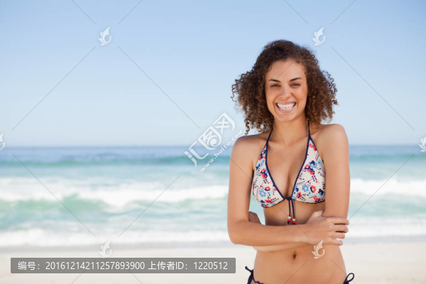 站在海邊的年輕女子微笑著雙臂交叉