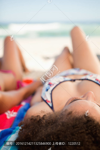 回頭看一位年輕漂亮女子躺在沙灘巾前的大海