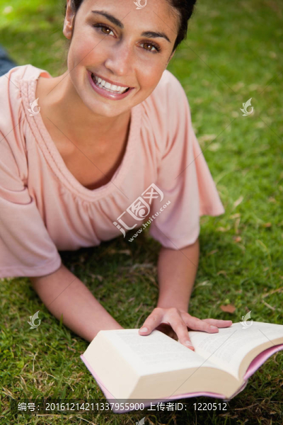 微笑的女人在看書時抬頭看著她躺下